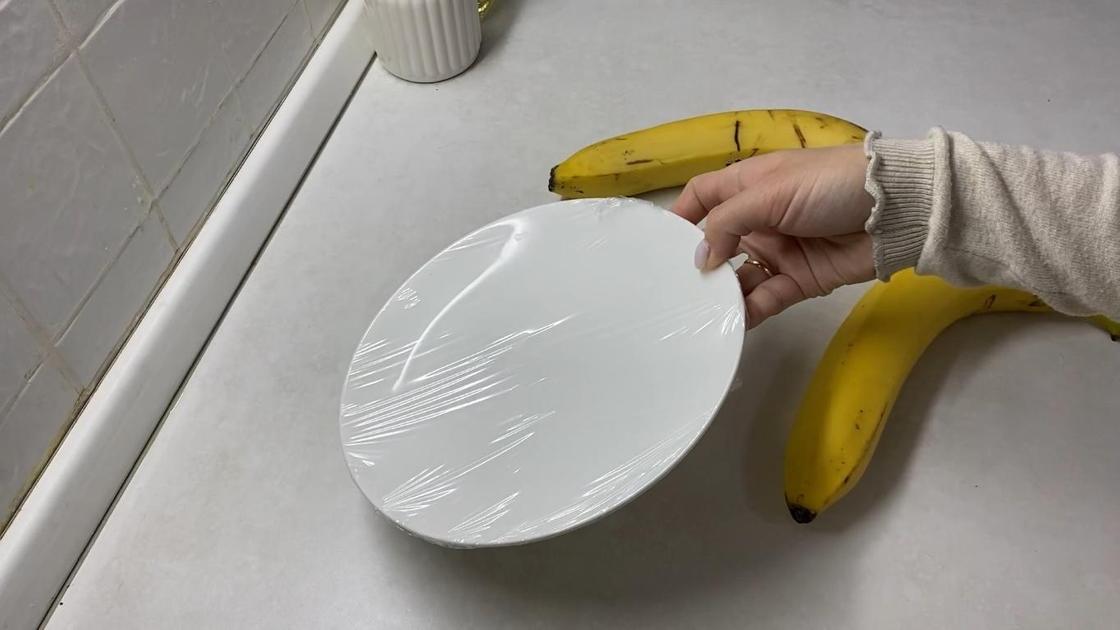 Тарелка в пищевой пленке, два банана на столе