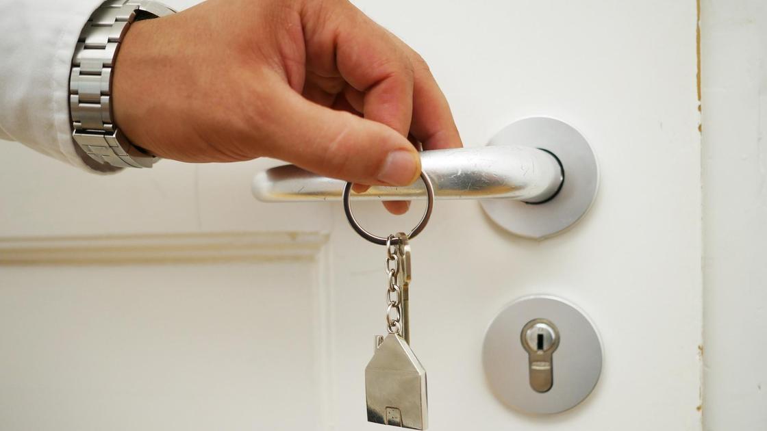 Человек открывают ключем дверь квартиры
