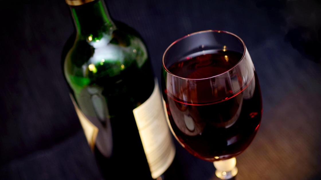 Бокал вина стоит рядом с бутылкой на столе