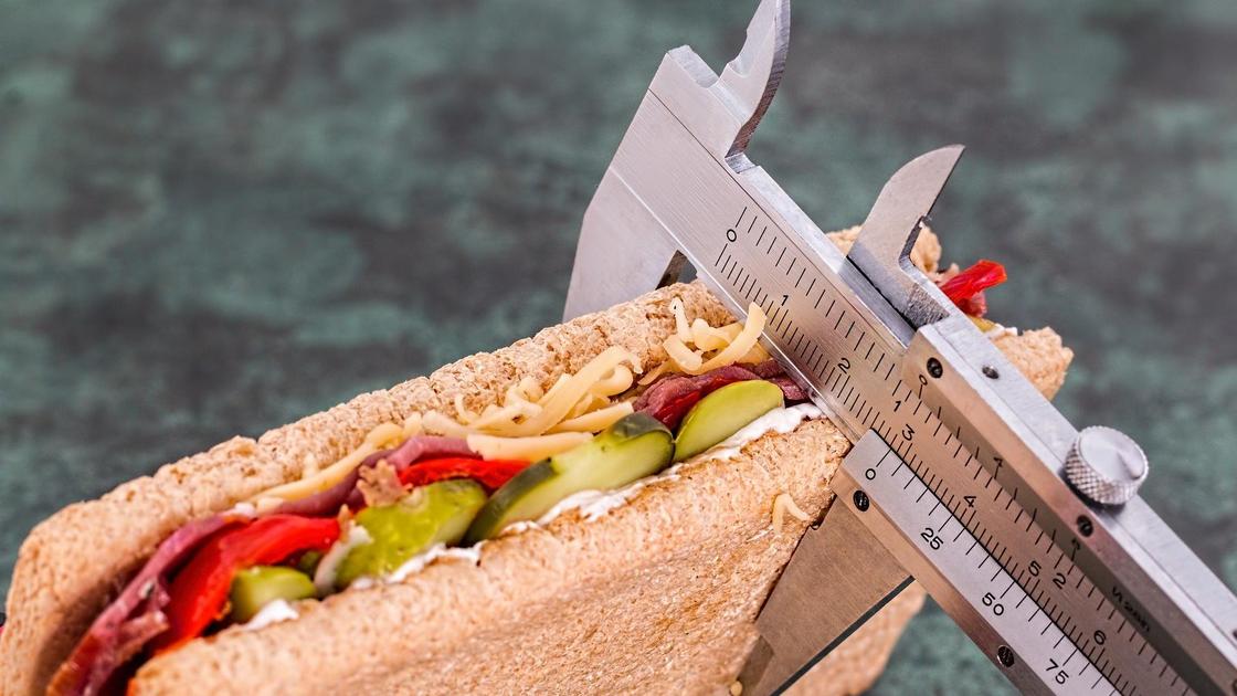 Сендвич и весы на сером фоне