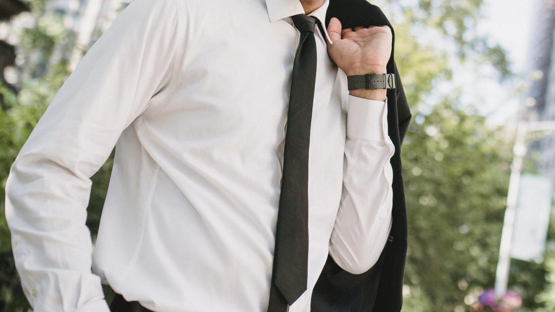 Мужчина в рубашке и с галстуком стоит на улице
