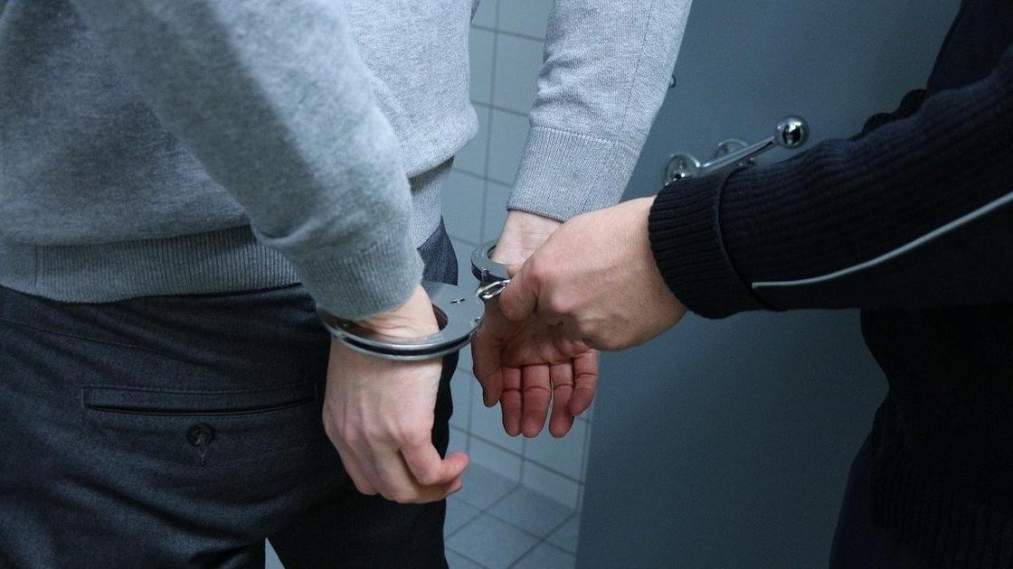 Полицейский надевает наручники задержанному