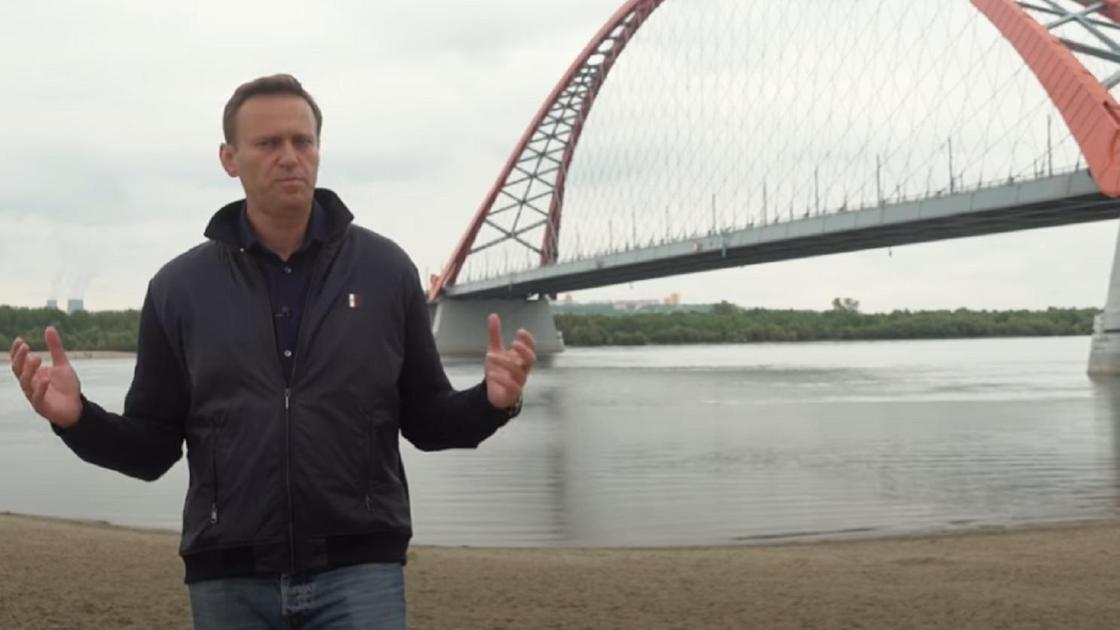Алексей Навальный на фоне моста в черной куртке