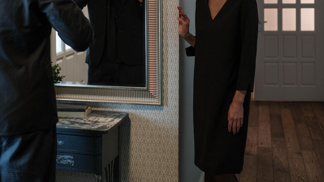 Мужчина и женщина в черной одежде стоят в квартире