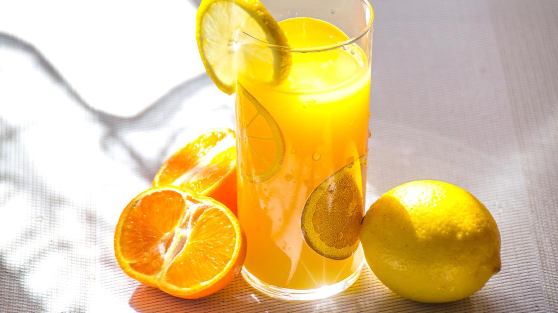 Стакан с апельсиновым соком, лимон и апельсины