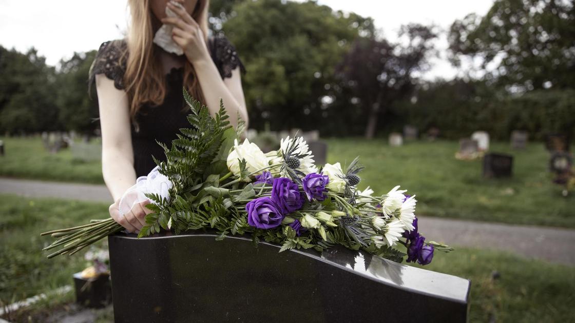 Девушка с букетом цветов на фоне кладбища