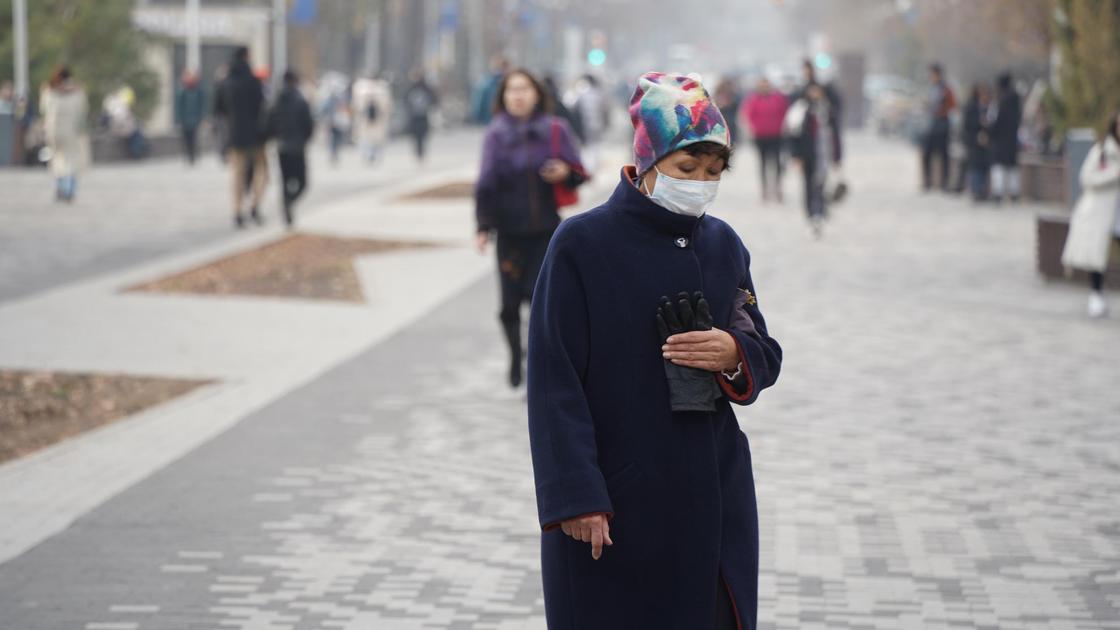 Женщина в маске с кошельком стоит на улице