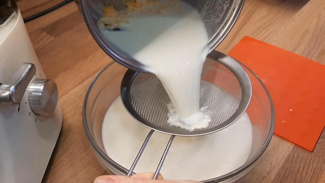 Молоко из кастрюли выливают на сито, установленное на стеклянной миске