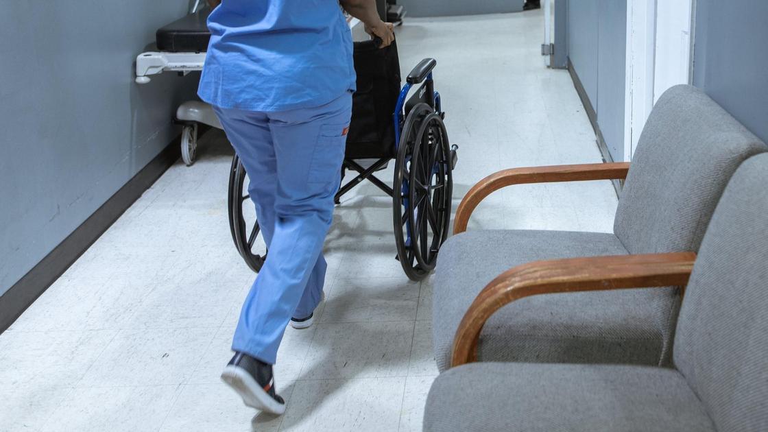 Медик везет по коридору инвалидную коляску