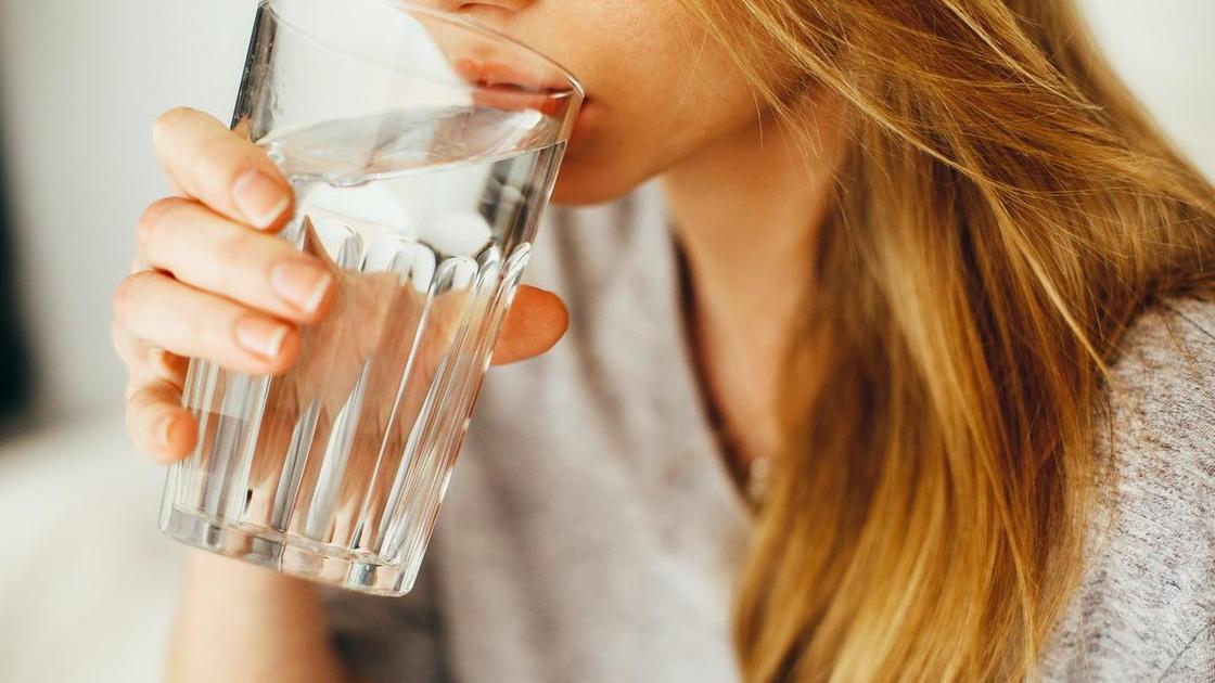 Девушка пьет воду из бокала
