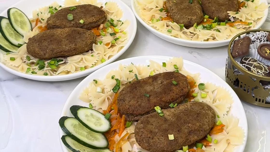 На тарелках сервированы котлеты с макаронами и овощами