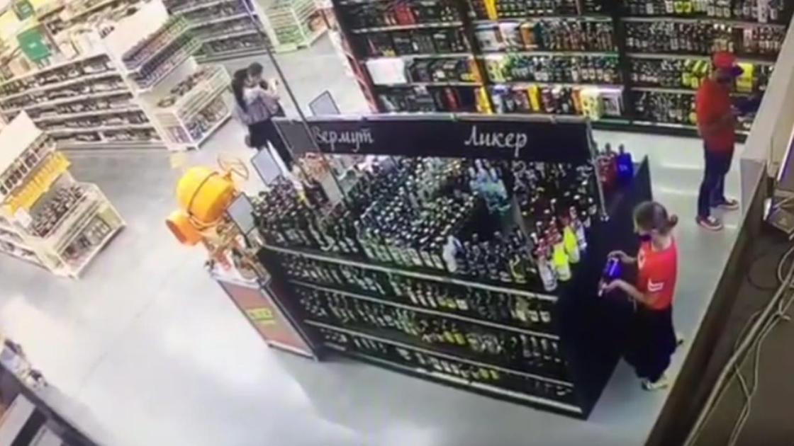 женщина крадет бутылку с виски