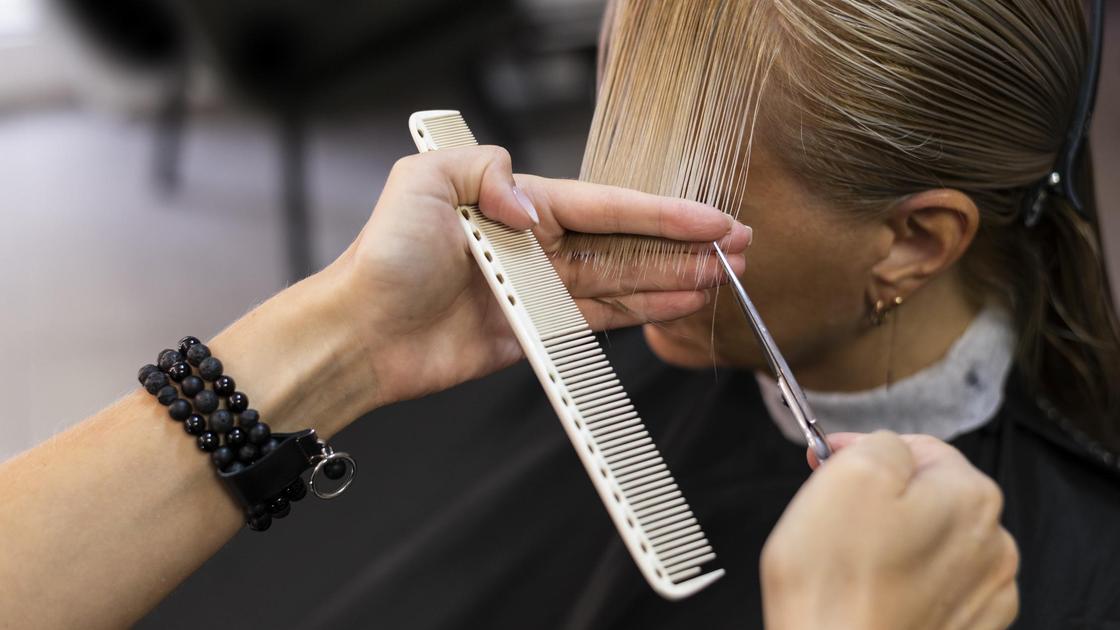 Парикмахер стрижет кончики волос