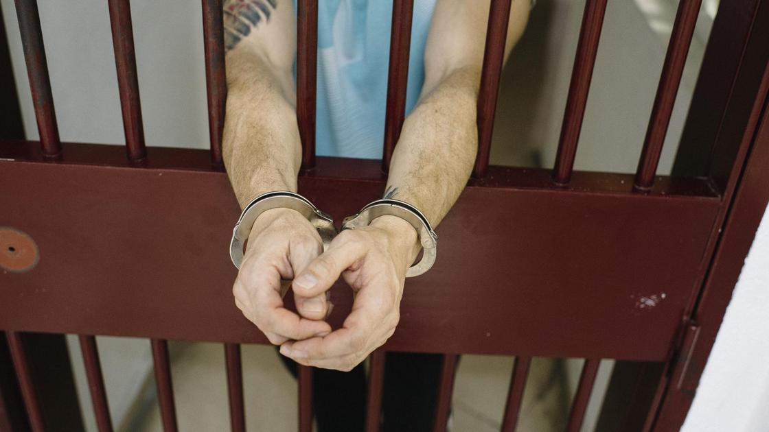 Мужчина в наручниках в тюрьме