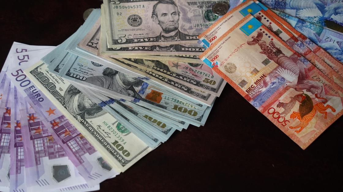 Банкноты евро, долларов и тенге лежат на столе