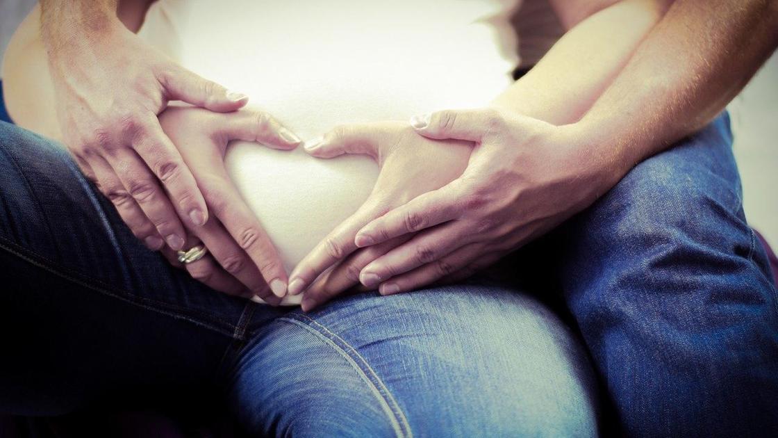 Пара держит руки на животе беременной женщины