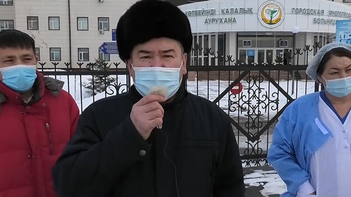 Трое человек в масках стоят перед зданием больницы