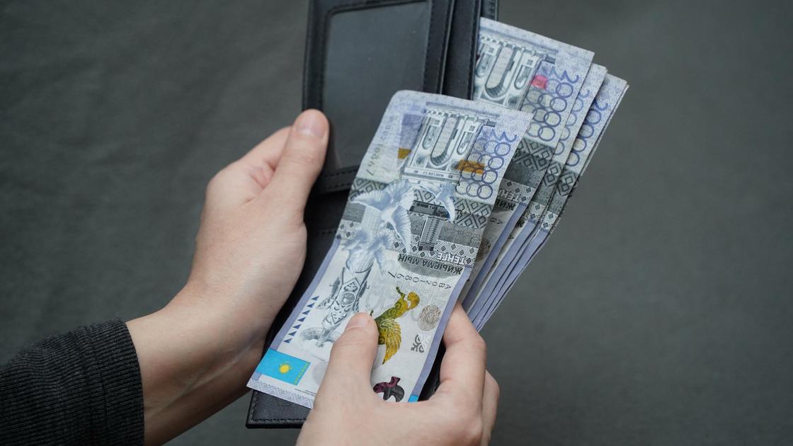 Человек держит в руках бумажник с деньгами