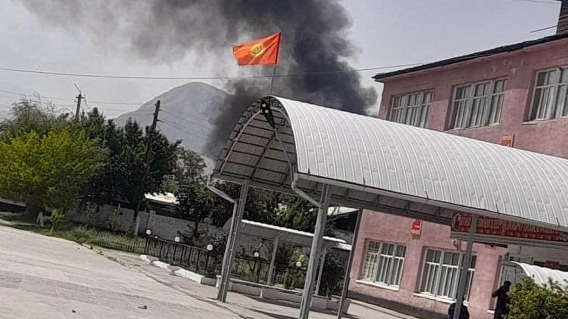 Дым стелется на фоне здания с флагом Кыргызстана