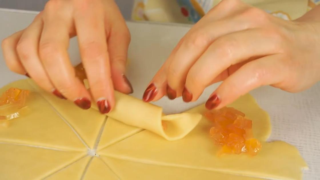 Девушка скручивает тесто с начинкой в рогалик