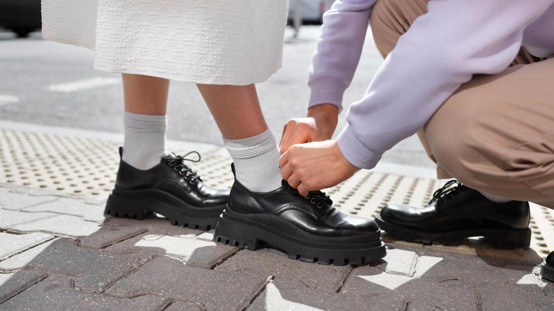 Мужчина завязывает девушке на туфлях шнурки