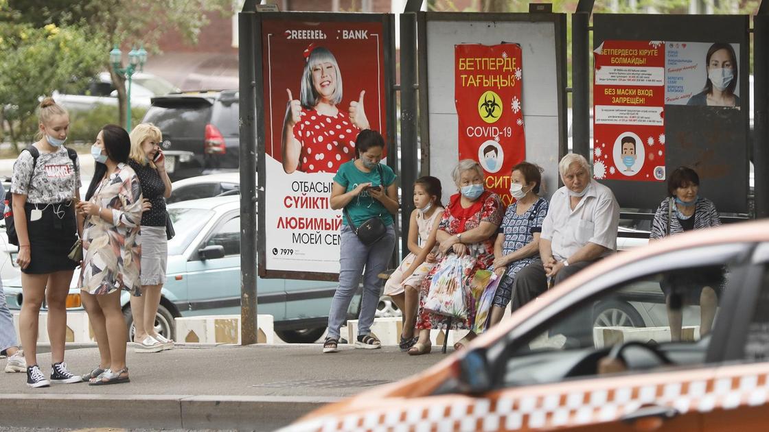 Люди стоят на остановке в Алматы