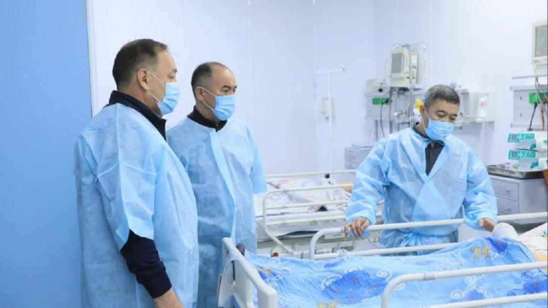 Трое мужчин в больничной палате возле детской койки