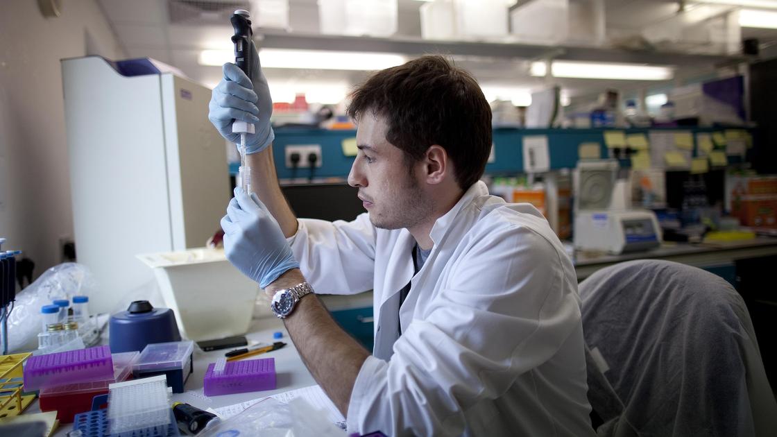 Мужчина в белом халате сидит в лаборатории