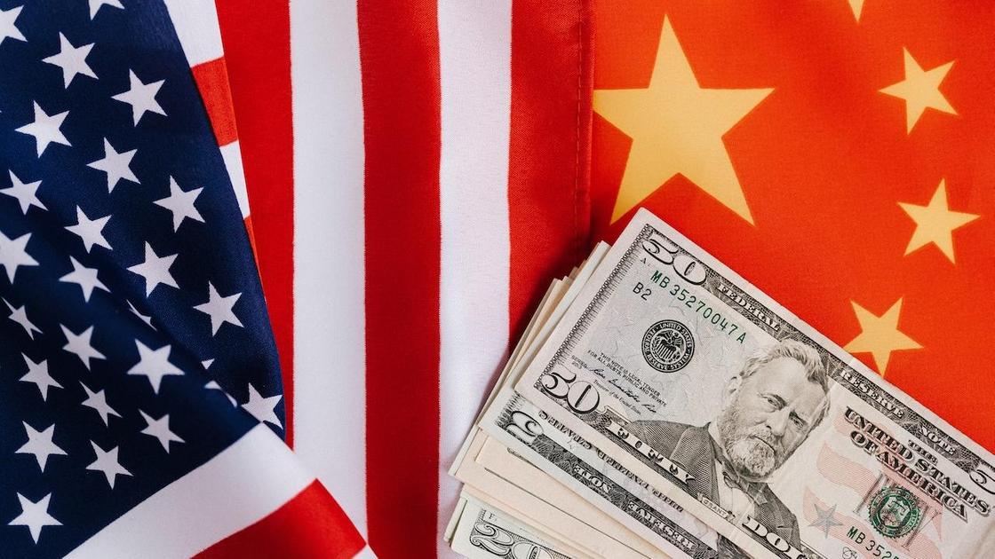 Доллары лежат на фоне флагов США и Китая
