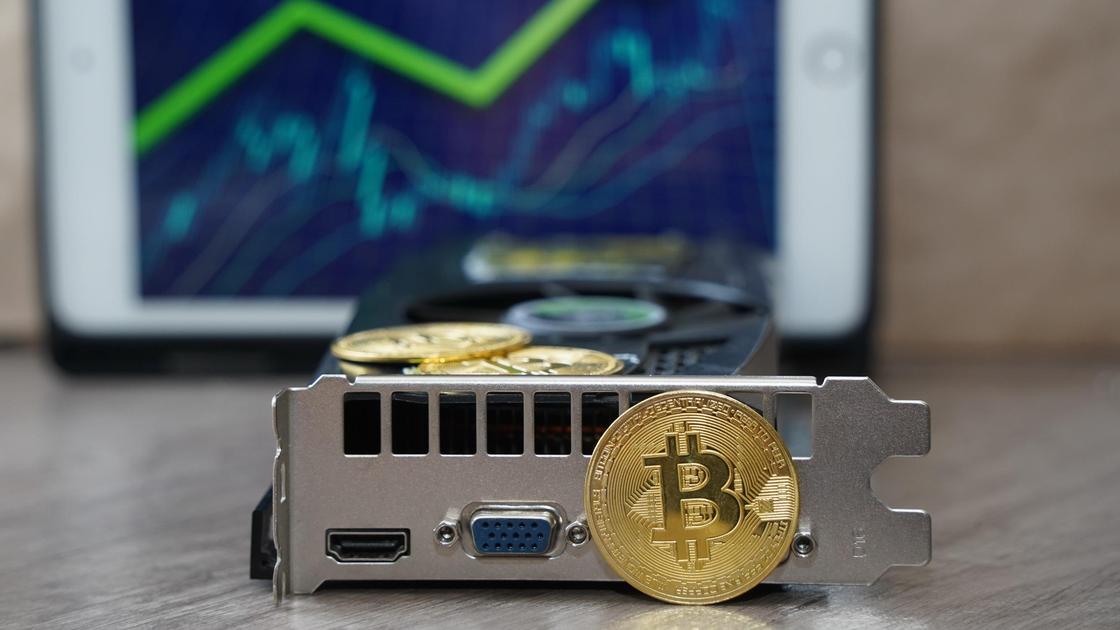 Видеокарта и биткоин в виде монет лежат на столе