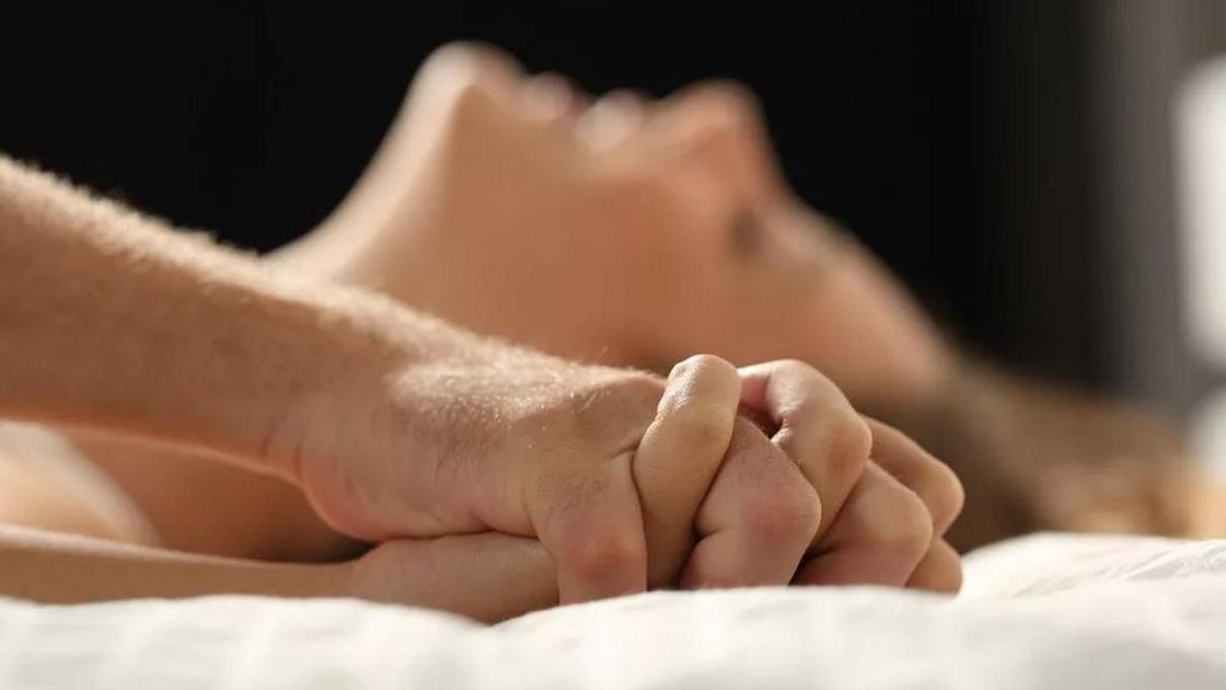 сцепленные руки мужчины и женщины, женщина лежит на кровати