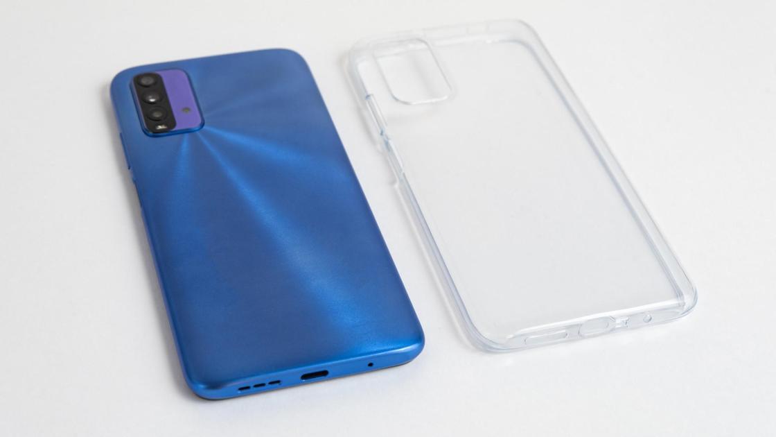 Рядом лежит синий смартфон и прозрачный силиконовый чехол