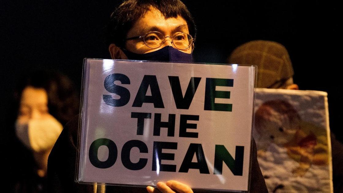 Мужчина держит в руках плакат с надписью "Спасем океан""