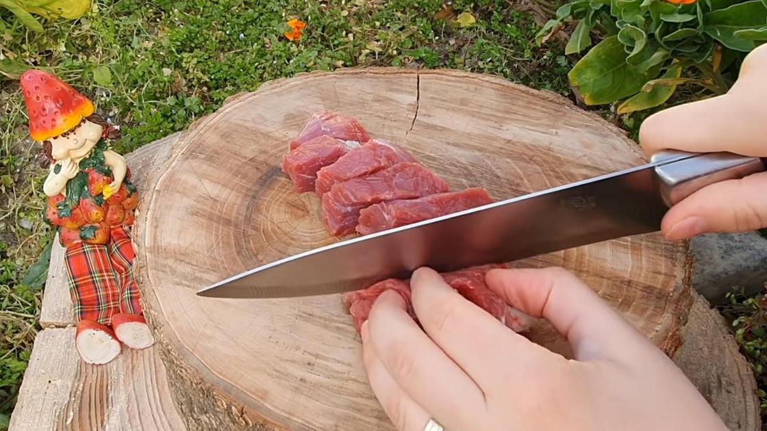 Мякоть баранины нарезают ножом на деревянном срубе