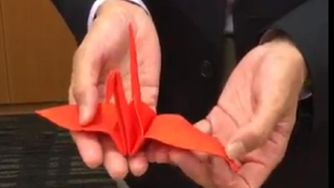Красный журавлик оригами в руках