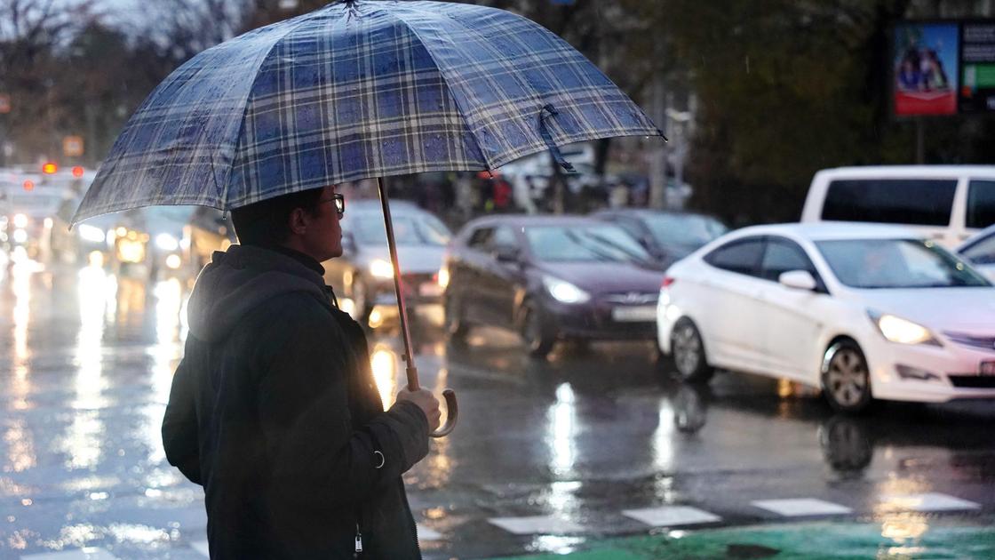 Мужчина с зонтом под дождем