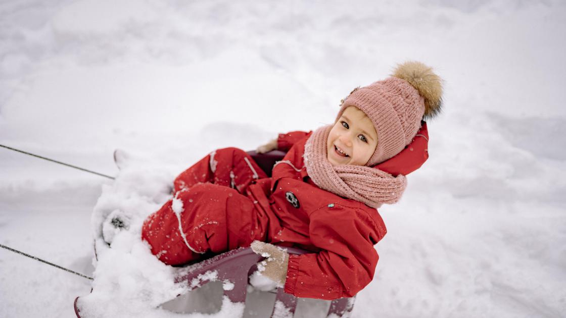 Ребенок зимой катается на санках
