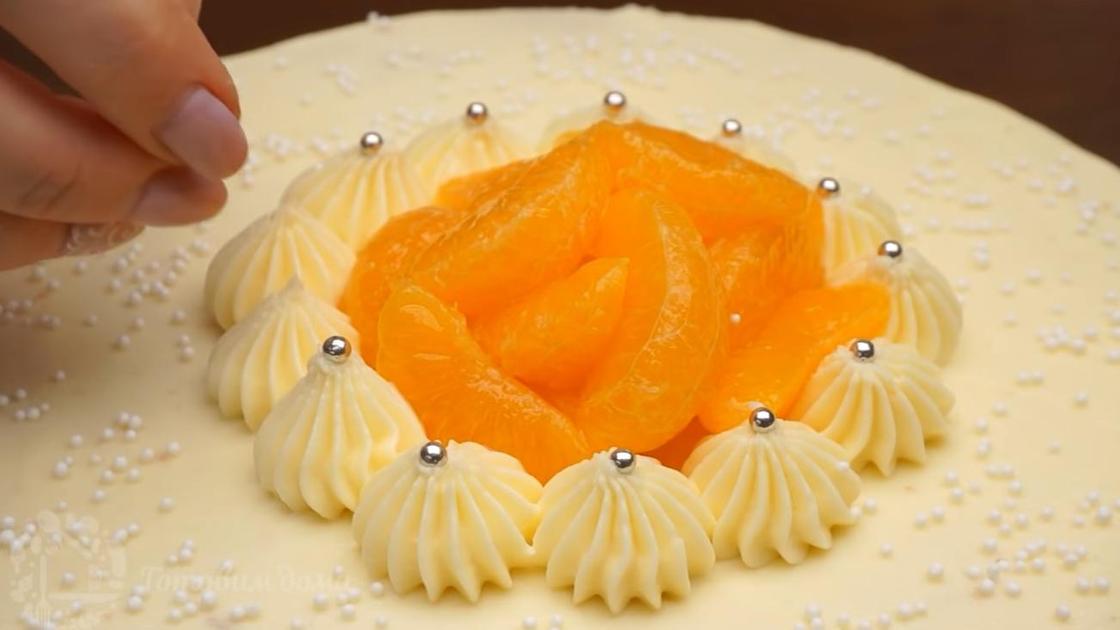Торт украшен кремовыми звездочками, мандариновыми долькам и кондитерской посыпкой