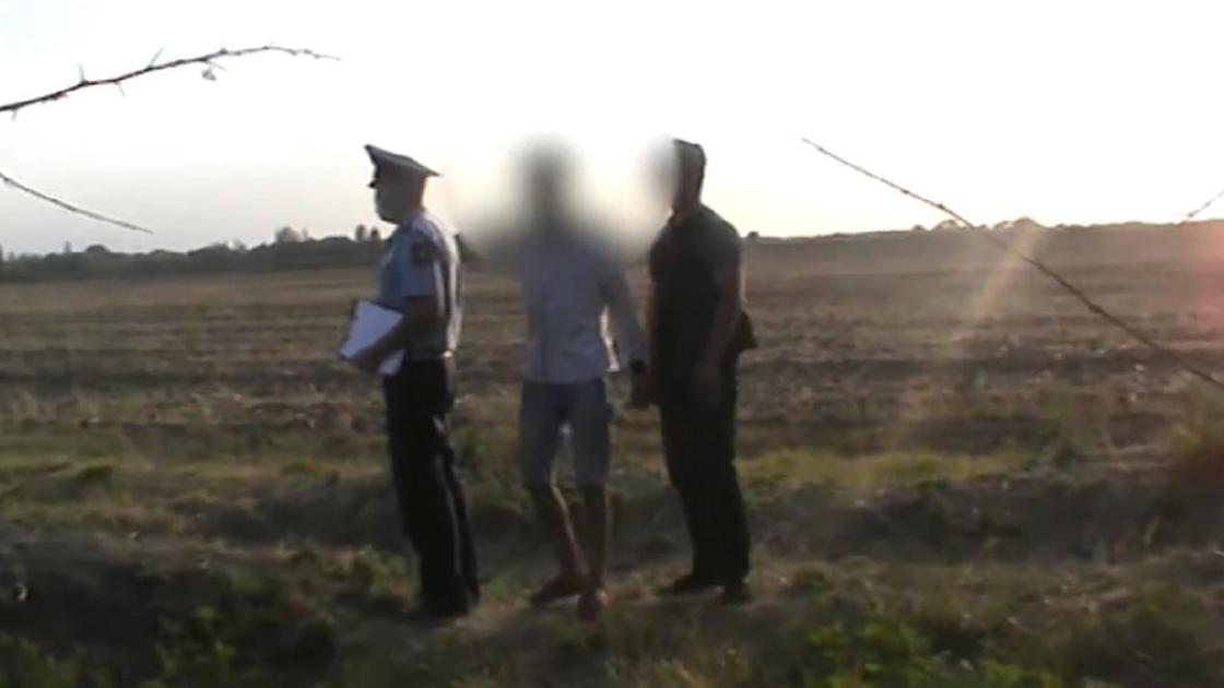 Полицейский и задержанные стоят в поле