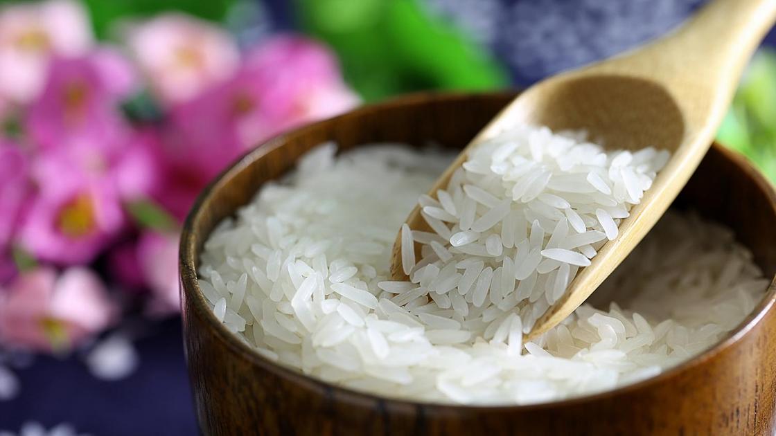 Белый рассыпчатый рис в деревянной миске с ложкой