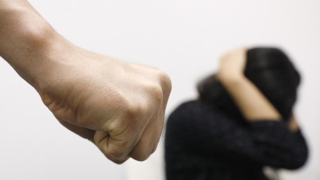 Женщина укрывается руками от мужского кулака