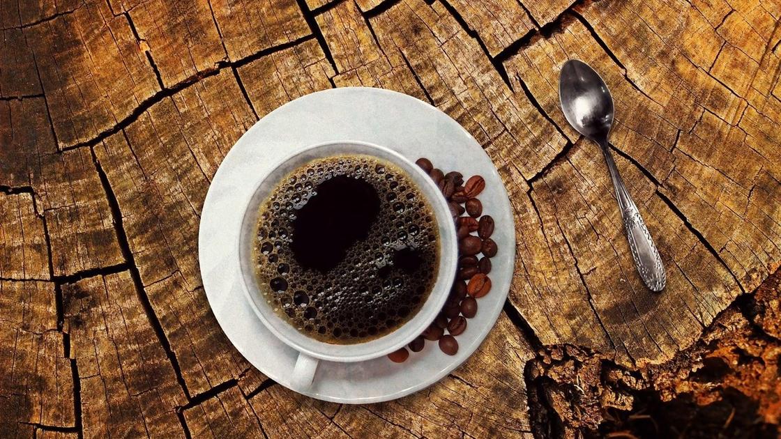 Кофе в чашке с блюдцем, кофейные зерна, ложка