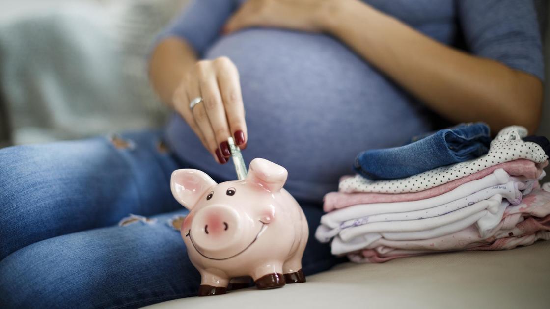 Беременная женщина складывает деньги в копилку
