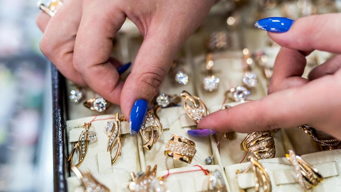 Золотые серьги на прилавке показывает продавец