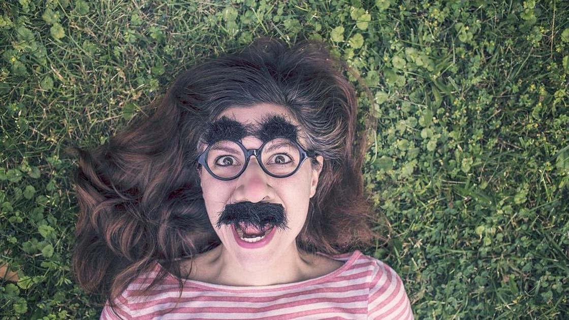 Девушка смеётся в маске с усами Девушка смеётся в маске с усами