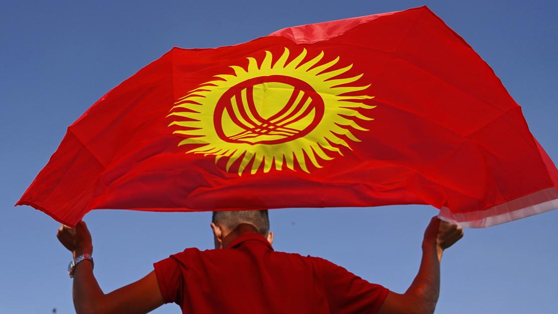Мужчина держит флаг Кыргызстана