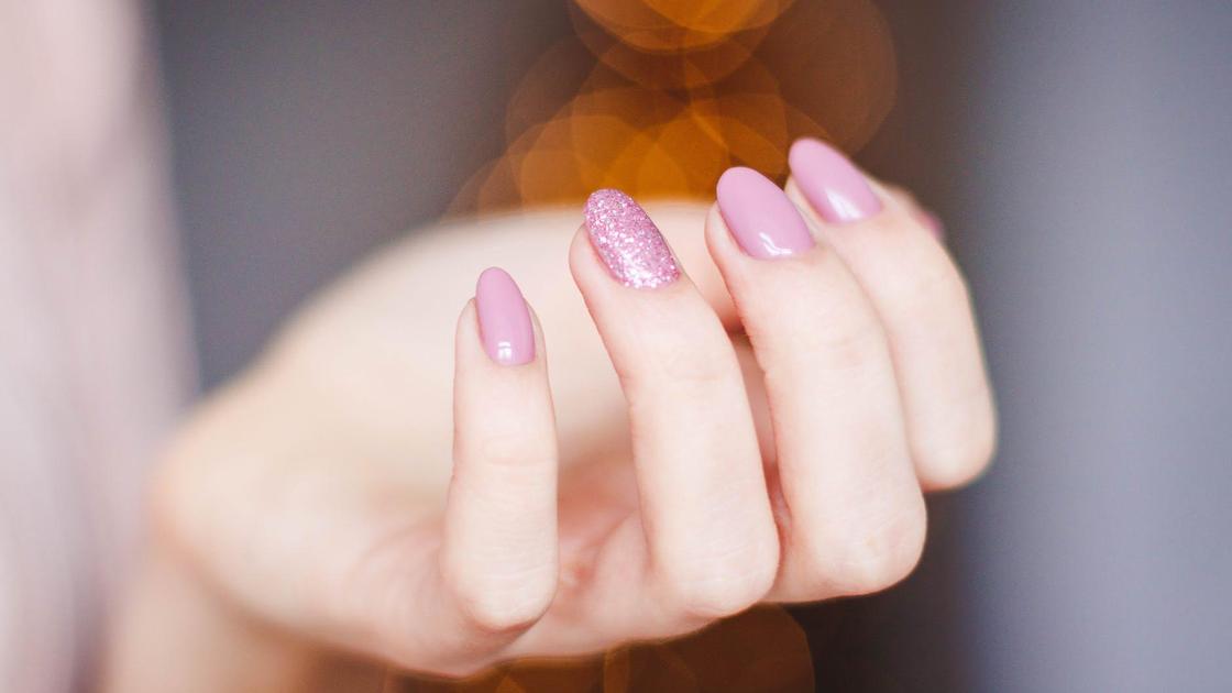 Женская рука с маникюром розового цвета