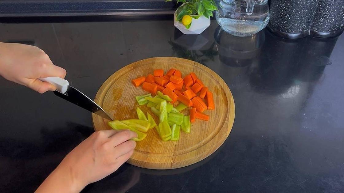 Морковь и перец режут на разделочной доске