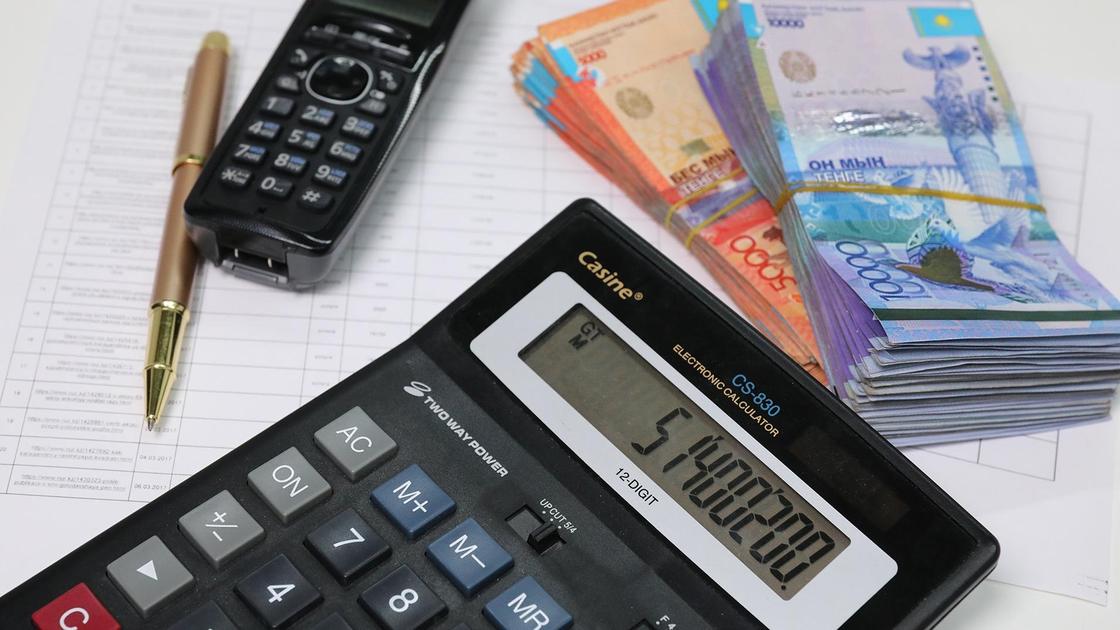 калькулятор лежит на столе рядом с пачкой денег