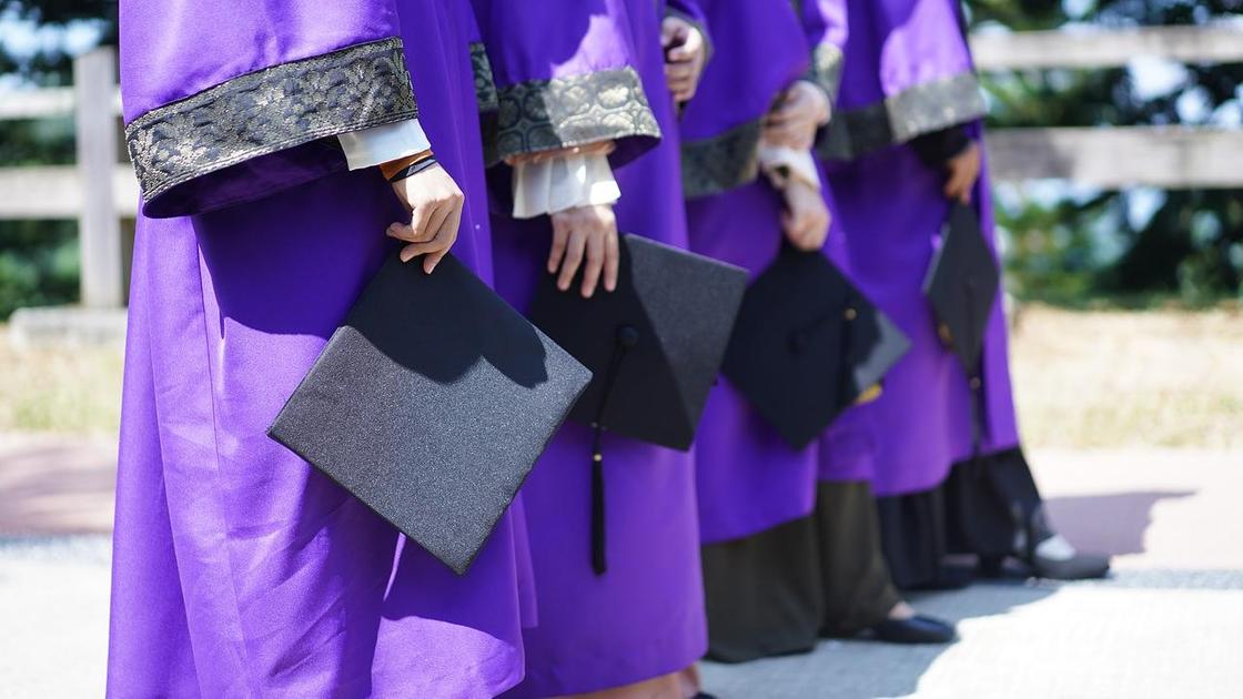 Студенты стоят на выпускном в мантиях